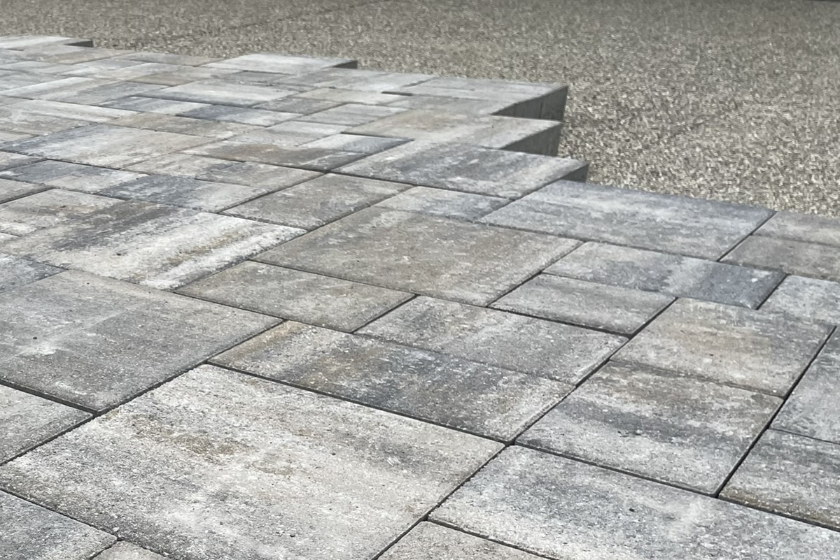 Terrassen- & Wegebau: Pflaster aus Beton in der Farbe grau im Bauprozess für eine Einfahrt