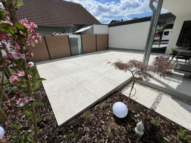 Terrasse aus Schellevisplattenbelag in creme mit Sichtschutz aus ASlu-Rhombus und Glaselementen