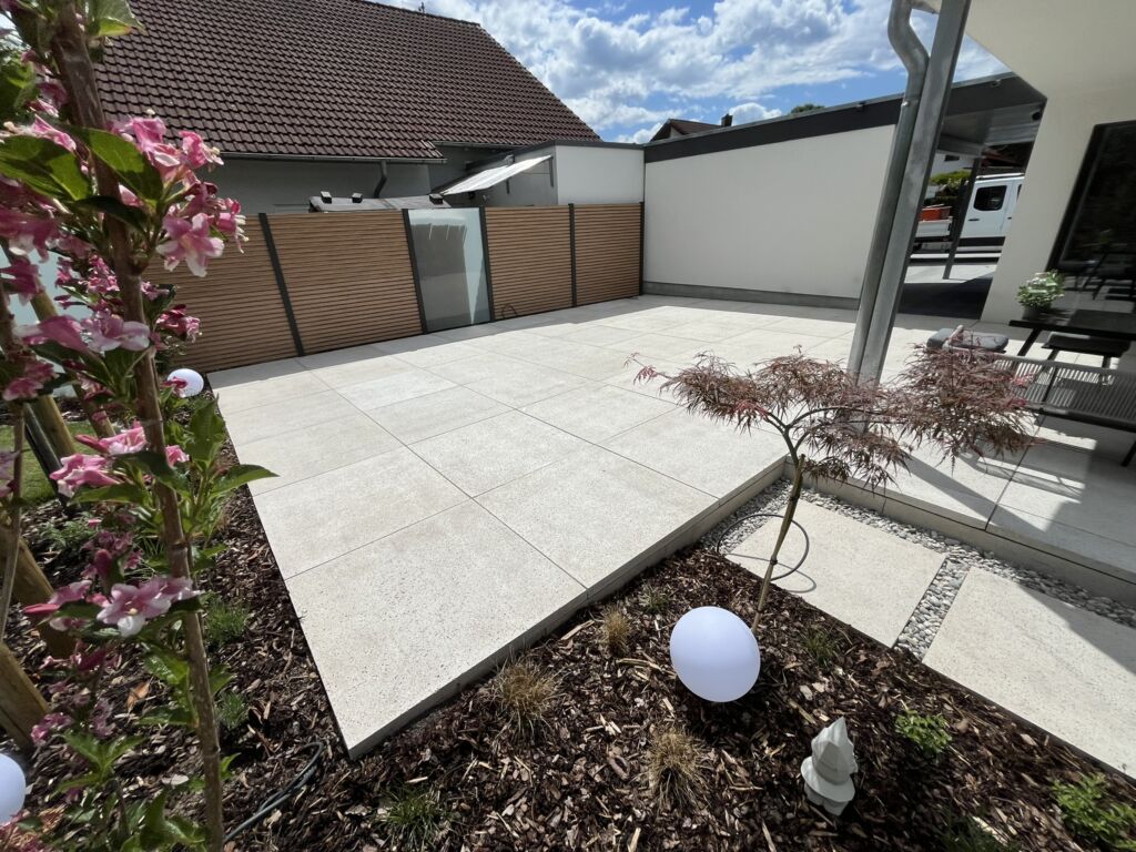 Terrasse aus Schellevisplattenbelag in creme mit Sichtschutz aus ASlu-Rhombus und Glaselementen