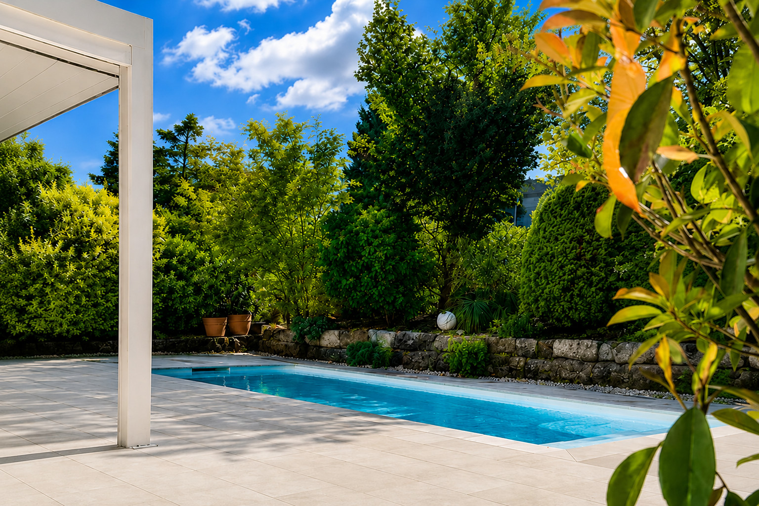 Exclusiver Poolgarten Hochwertiger Wellnessgarten mit Pool, heller Terrasse, Pergola und üppiger grüner Bepflanzung bei Sonnenschein