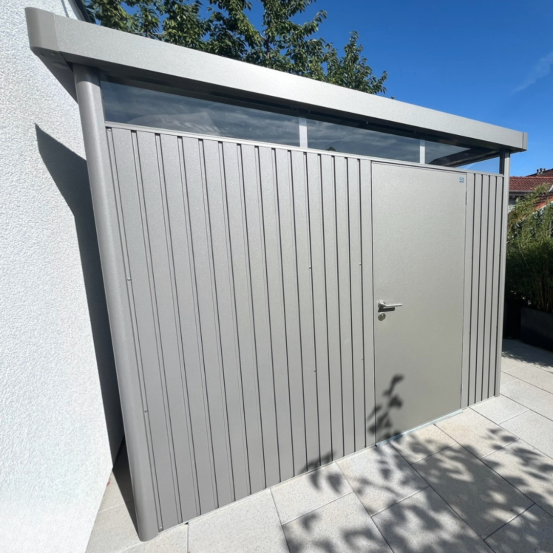 Ordnung mit moderner Linie - Gartenextra: Biohort-Hütte Moderner Geräteraum in Grau mit Tür, Glasoberlicht und heller Plattenfläche am Wohnhaus