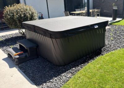 Moderner Whirlpool im Garten mit Kiesfläche, Rasen und klar gestalteter Außenanlage